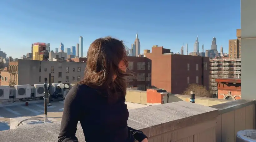 NYC rooftop view, a woman contemplates the city's skyline
