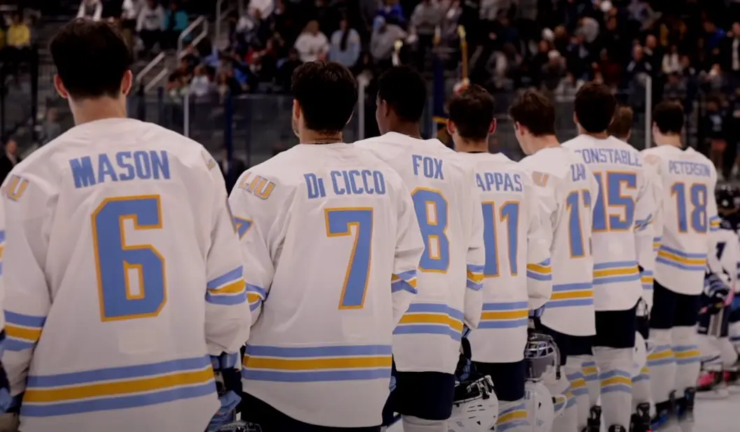 A line of hockey players, their white jerseys accented with light blue and gold stripes