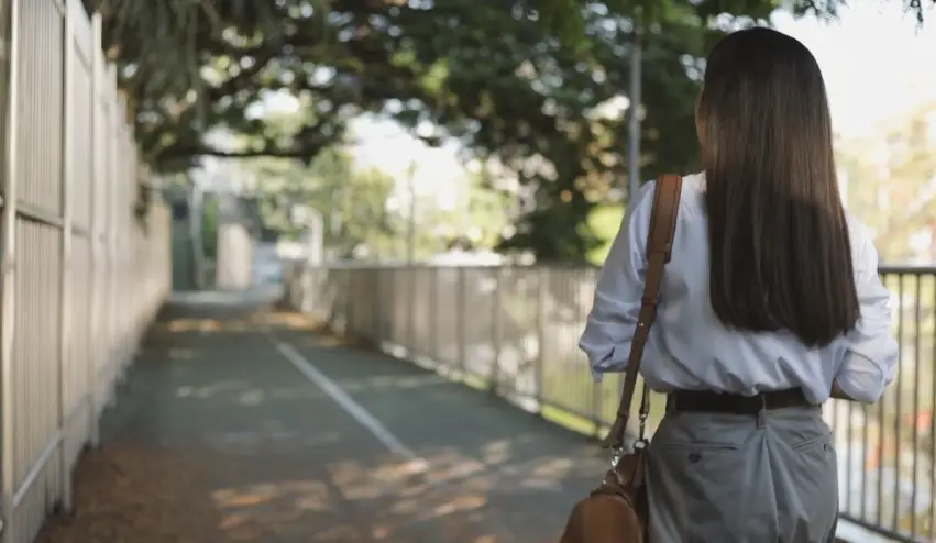 Gray pants and a light blue button-down shirt are visible on a woman walking away