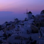 The Aegean Sea meets the horizon as the sun dips below the Santorini skyline