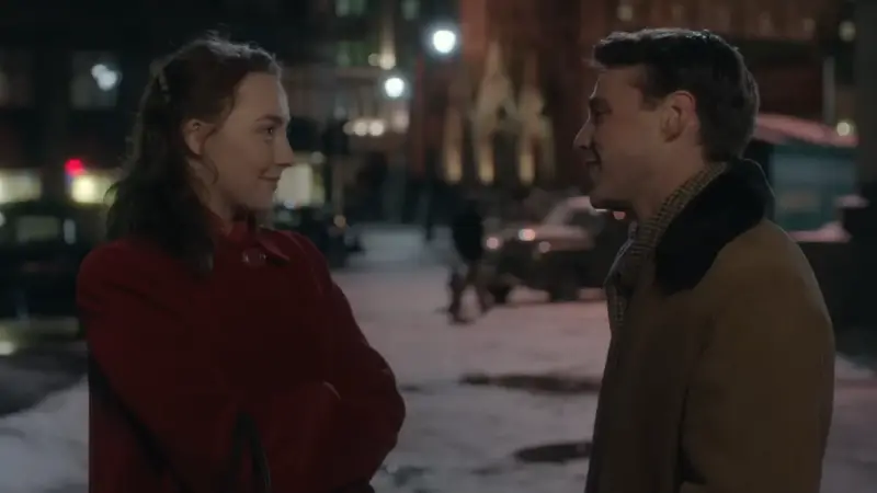 A young woman and man stand facing each other on a snowy Brooklyn street at night