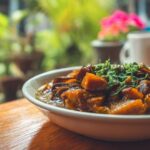 Close-up of a bowl of vegan vegetable stew served on a wooden table in a restaurant