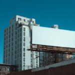 Large blank billboard in Brooklyn with tall buildings in the background under a clear blue sky