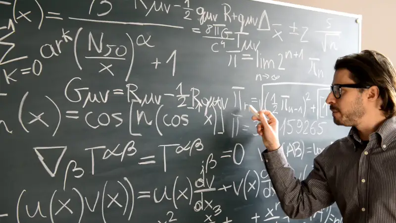 A professor explains advanced mathematical equations on a chalkboard in a university classroom