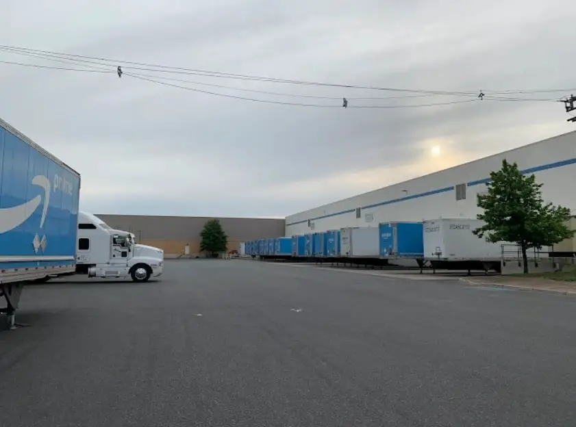 Amazon Prime trailers lined up outside a large warehouse facility in New Jersey, with trucks and loading docks visible