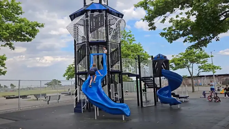 Midland Beach Playground with tall blue slides and kids playing near the waterfront area
