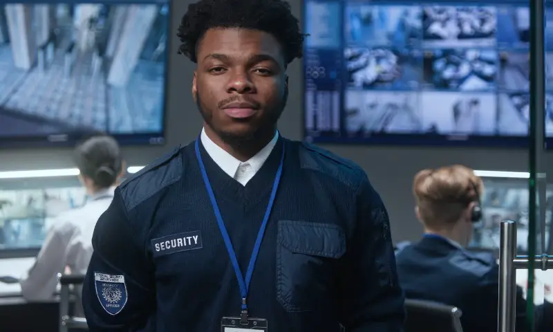 A man in uniform stands confidently in front of a security camera