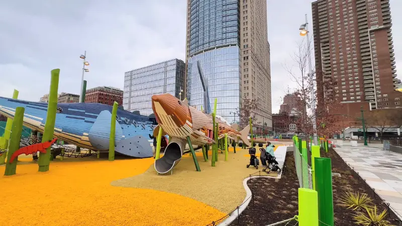 Pier 26 Science Playground with large fish-themed structures and kids playing near the Hudson River