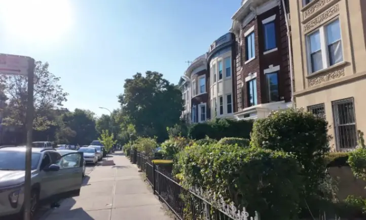 A street lined with parked cars and a row of residential houses on either side