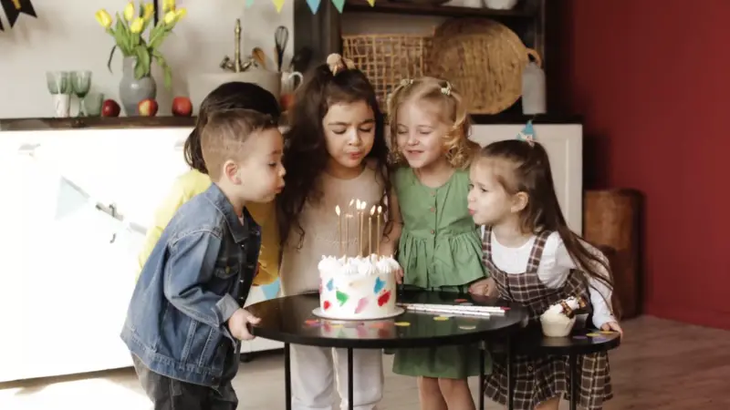 Kids gathered around a cake blowing out candles at a birthday celebration in Brooklyn